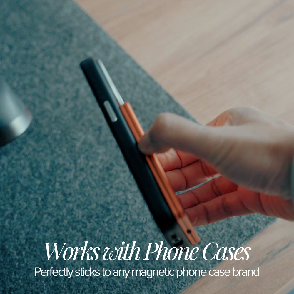 Person holding a phone with an orange magnetic phone case on a blurred background