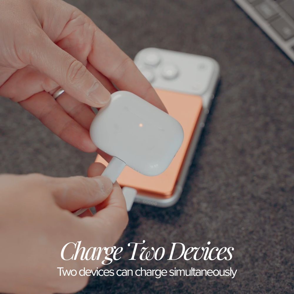 Person plugging a white charging cable into a device on a desk.